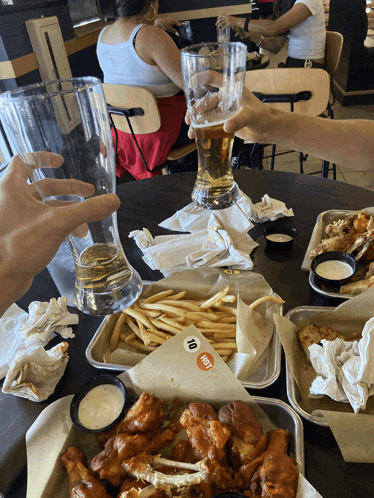 a table with a tray of chicken wings and a tray of french fries with a sticker that says hot