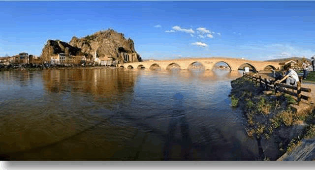 a bridge over a river with a mountain in the background and a city in the background .