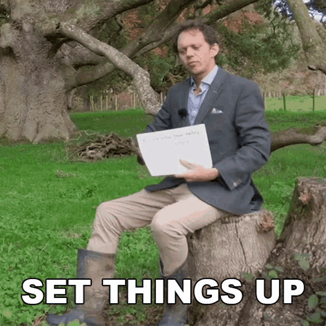 a man in a suit is sitting on a tree stump holding a piece of paper that says " set things up " on it