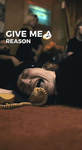 a poster for give me a reason shows a man laying on the floor talking on a phone