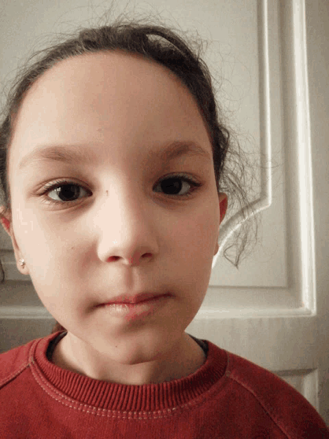 a close up of a girl 's face with a red shirt on