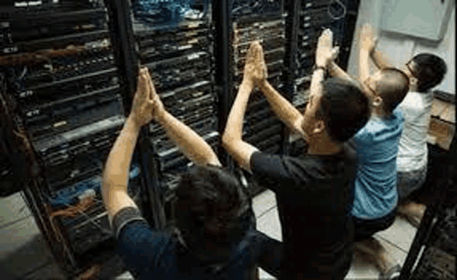 a group of people are giving each other a high five in a server room .