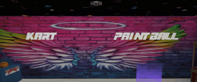 a brick wall has wings painted on it and the words kart paintball