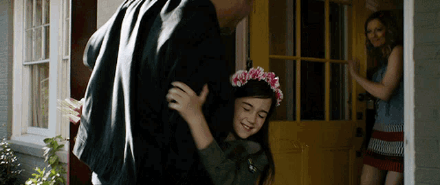 a girl wearing a flower crown is hugging a man