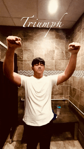 a young man flexes his muscles in a bathroom with the word triumph written on the ceiling