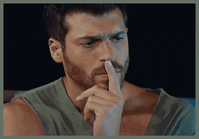 a man with a beard holds his finger to his lips