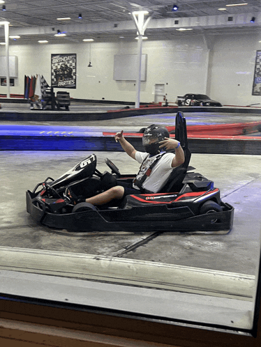 a man in a go kart with a birthday party poster on the wall