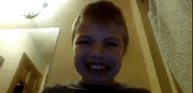 a young boy is smiling at the camera in a dark room