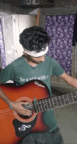 a boy wearing a green shirt that says " be a girl with " holds a guitar