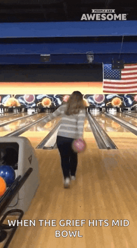 a woman throws a bowling ball in a bowling alley with the words when the grief hits mid bowl below her