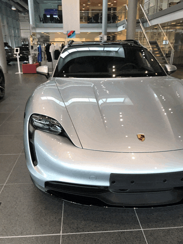 a silver porsche is parked in a car dealership