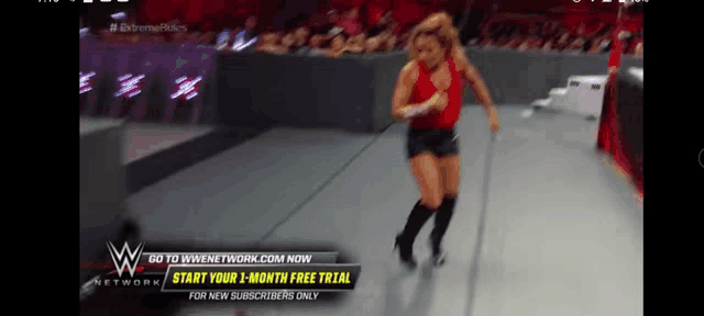 a woman in a red tank top and black shorts is running on a wrestling mat