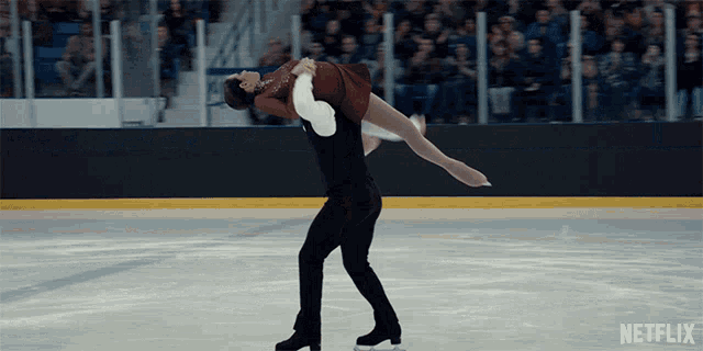 a man is holding a woman in his arms on a ice rink with a netflix logo in the background