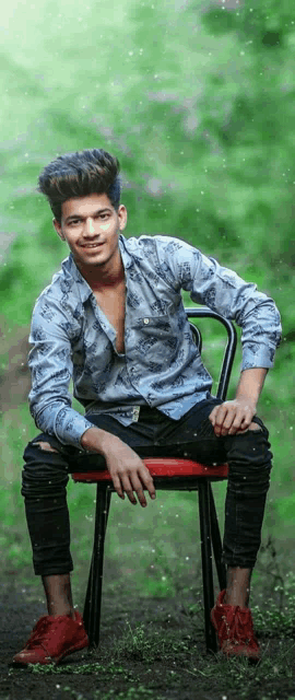 a young man in a blue shirt is sitting on a chair in the grass