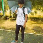 a young man is holding an umbrella while standing on a road .