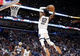 a basketball player is jumping in the air to dunk a basketball .