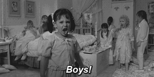 a black and white photo of a little girl standing in front of a group of children in a bedroom .