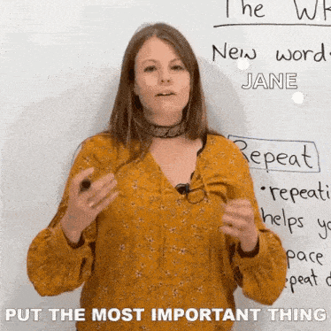 a woman is standing in front of a white board with the words put the most important thing on it .