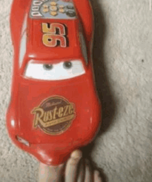 a person is holding a toy lightning mcqueen car on their foot .