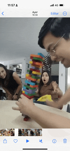 a phone screen shows a group of people playing a game called jenga