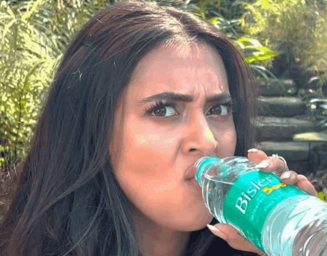 a woman drinking from a bisleri water bottle