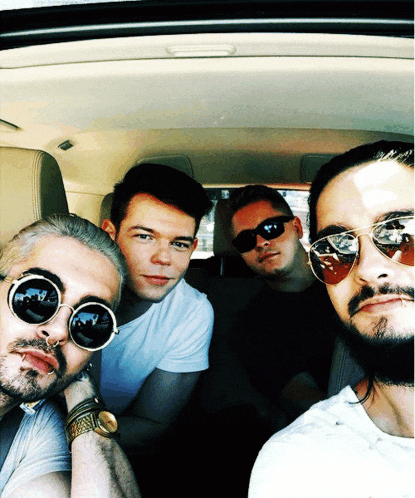 a group of men wearing sunglasses pose for a picture in a car