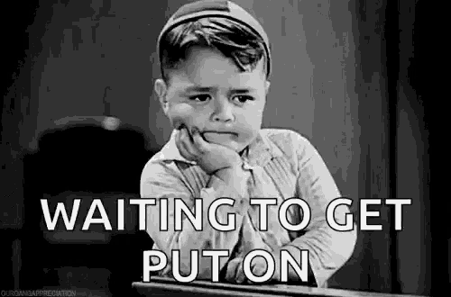 a black and white photo of a sad little boy sitting at a desk with his hand on his chin .