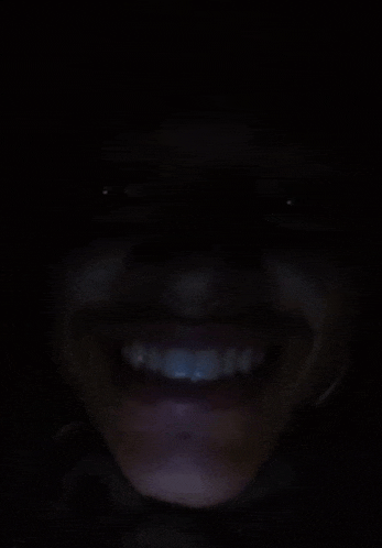 a close up of a woman 's face smiling in the dark