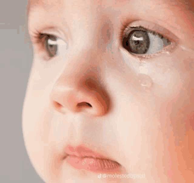 a close up of a baby 's face with a tear running down its eye .