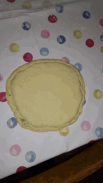 a circle of dough sits on a table with polka dots on it