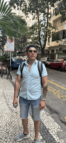 a man standing on a sidewalk with a no parking sign