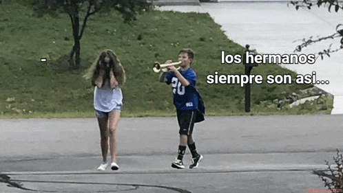 a boy is playing a trumpet while a girl looks on .