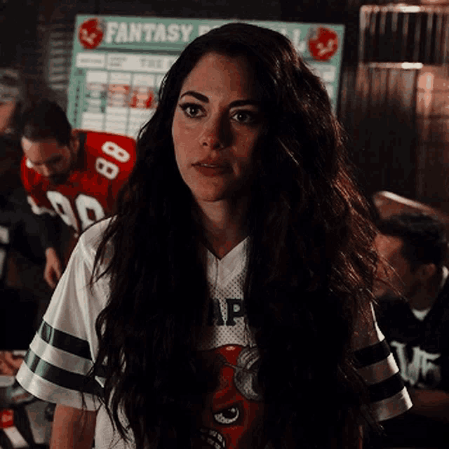 a woman with long hair is wearing a fantasy football shirt .