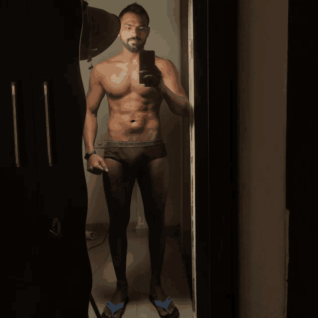 a shirtless man taking a selfie in a mirror