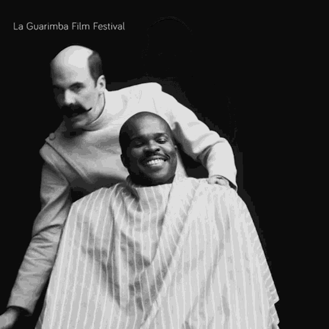 a black and white photo of a man getting his hair cut by a barber and the words la guarimba film festival on the bottom