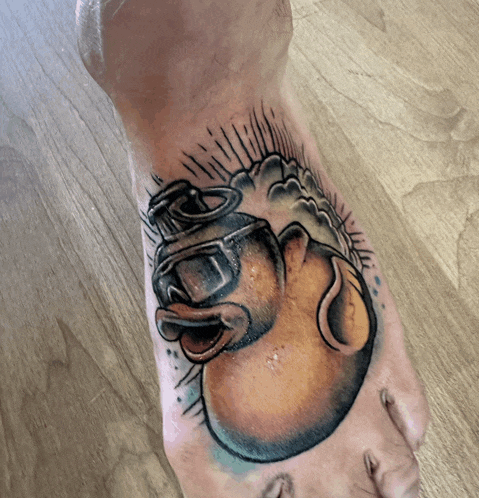 a person has a tattoo on their foot of a duck wearing a diving mask