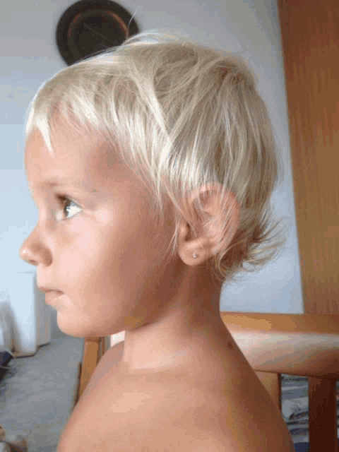 a little girl with short blonde hair has a pair of earrings in her ear