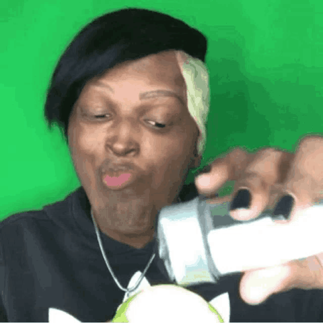 a woman is making a funny face while holding a bottle in front of her face .