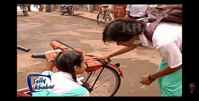 a boy petting a girl on the back of a bicycle with a tally khar logo on the bottom right