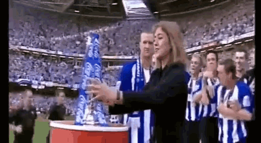 a group of people in blue and white striped shirts are standing in a stadium with a woman standing in front of them