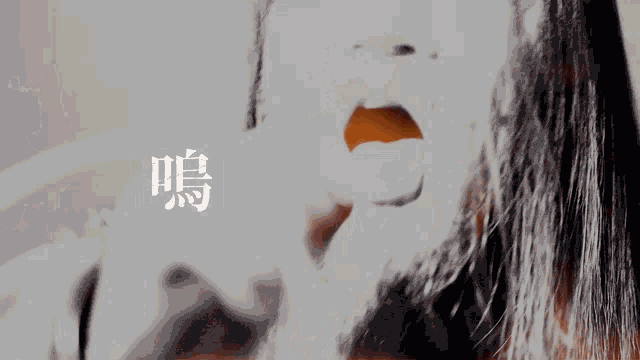 a woman with long hair is screaming in front of chinese writing