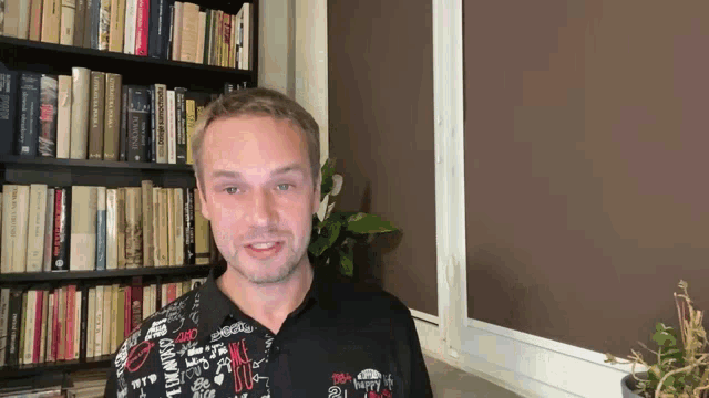 a man stands in front of a bookshelf with a shirt that says ' i am happy ' on the front