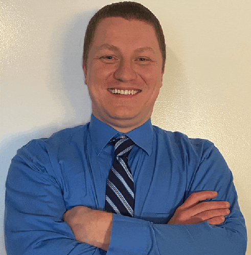 a man wearing a blue shirt and tie smiles for the camera