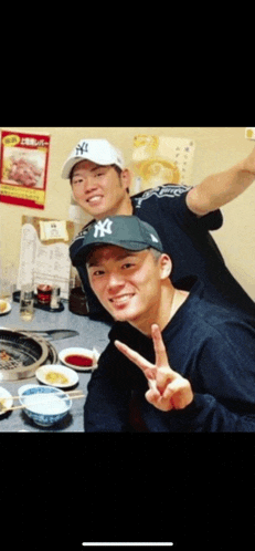 two men wearing ny hats pose for a photo