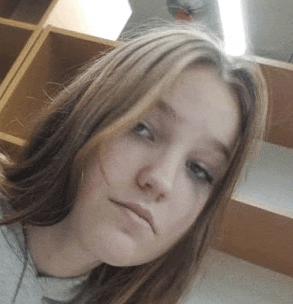 a young girl with long hair is taking a selfie in front of a wooden shelf .