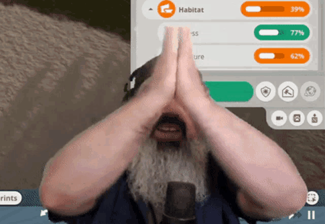 a man with a beard is covering his face with his hands in front of a screen that says habitat