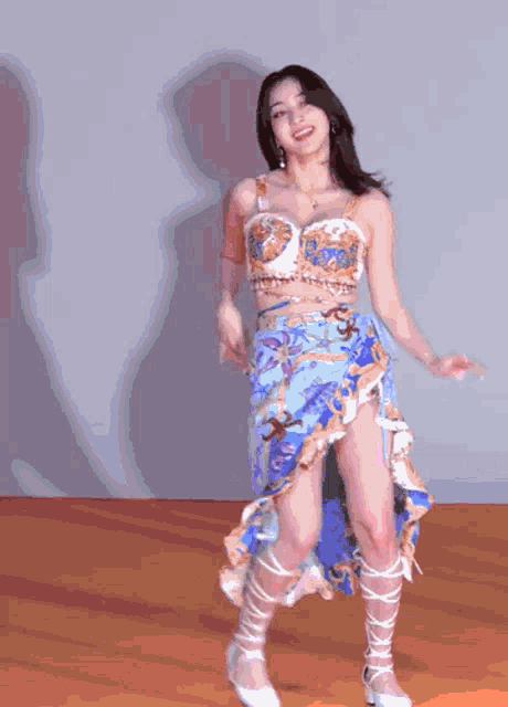 a woman in a blue skirt is dancing in front of a wall