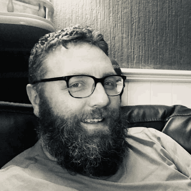 a man with a beard and glasses is smiling