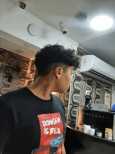 a man wearing a black shirt that says danger is real on it