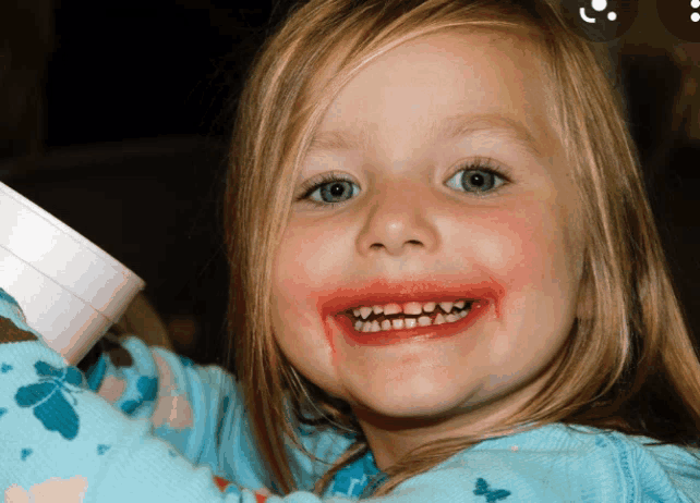 a little girl with blood on her face holds a white cup